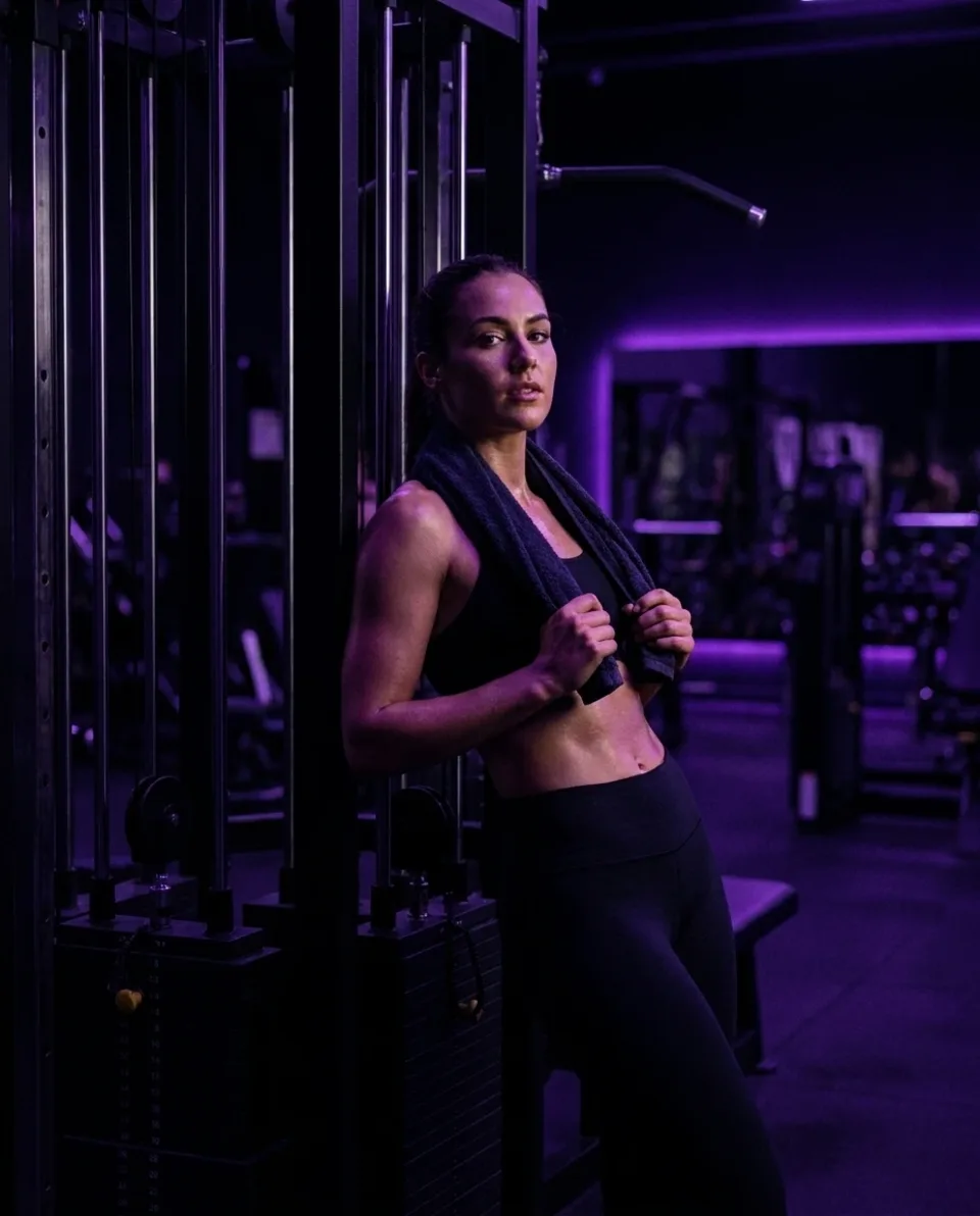 Mulher em pé com uma toalha ao redor do pescoço na academia