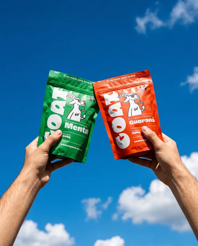 Duas mãos erguendo as embalagens Menta e Guaraná da Goat contra o céu azul