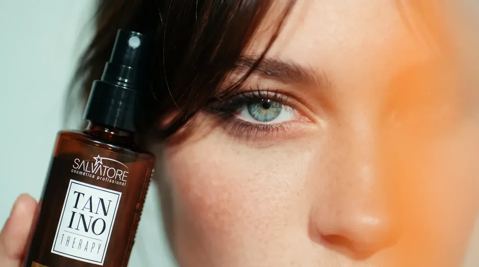 Mulher com a franja solta segurando o produto Tanino Therapy da HD Cosméticos perto do rosto