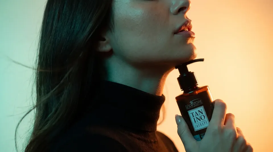 Mulher de perfil segurando o produto Tanino Therapy da HD Cosméticos junto ao queixo