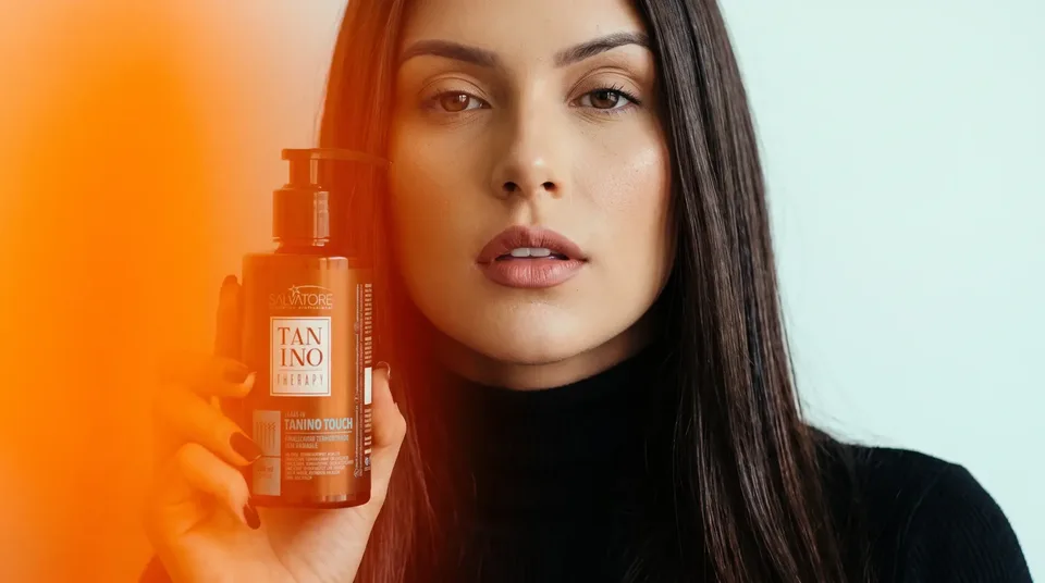 Mulher segurando o produto Tanino Touch da HD Cosméticos junto ao rosto